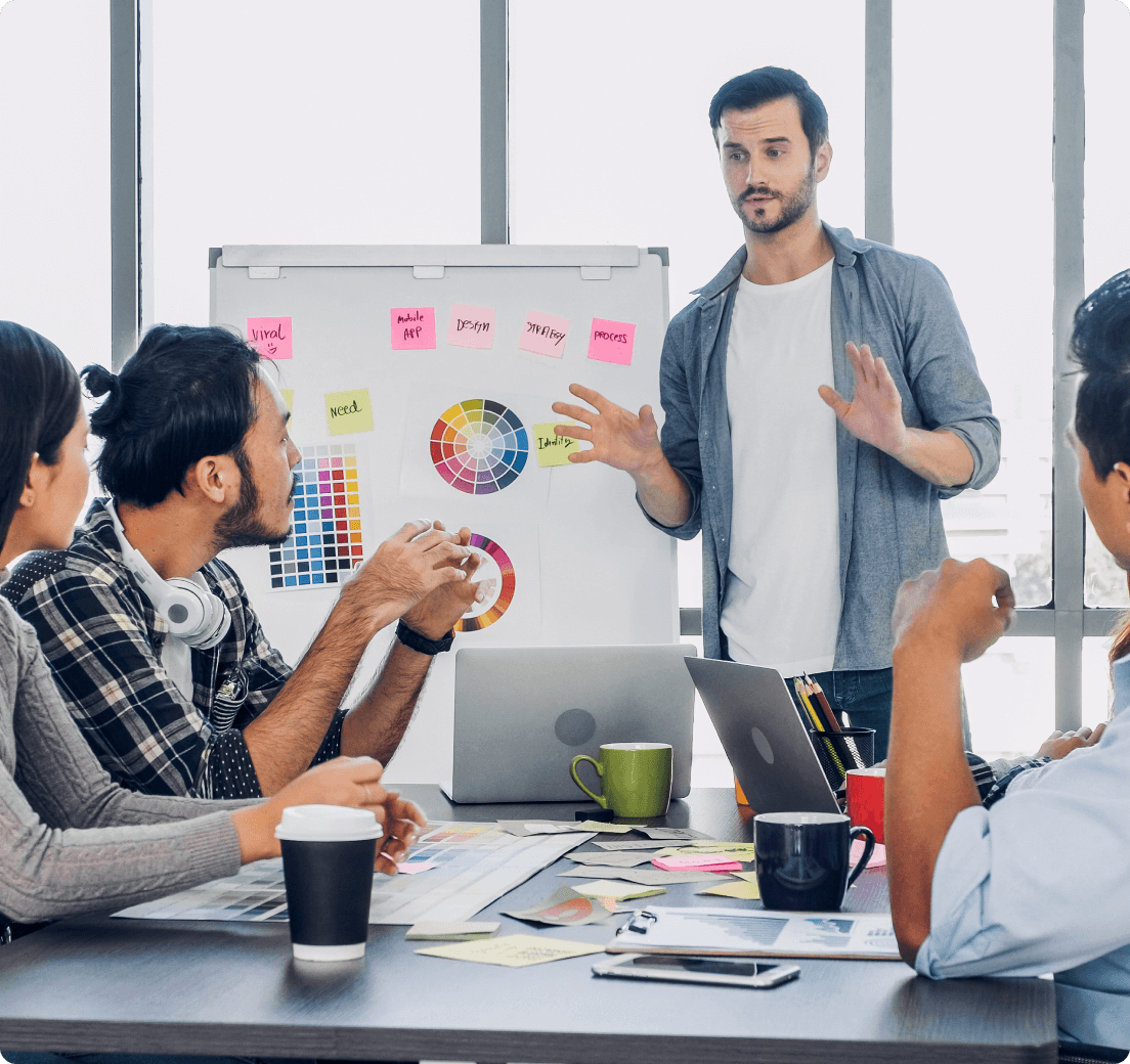 Team meeting: a man presents at a whiteboard covered in sticky notes